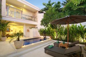 a house with a swimming pool and an umbrella at Villa Lamac in Legian