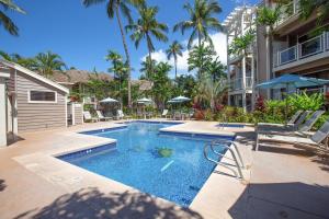 a pool with chairs and umbrellas next to a building at Wailea Grand Champions in Wailea