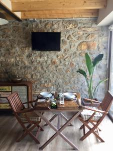 a table with two chairs and a tv on a stone wall at La Cabaña de Catalina in Sotres