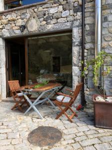 a patio with a table and chairs in a stone building at La Cabaña de Catalina in Sotres