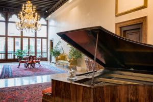 a large piano in a living room with a chandelier at Hotel Nani Mocenigo Palace in Venice