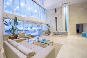 a lobby with a white couch and tables and windows at Oasis Atlantico Fortaleza in Fortaleza