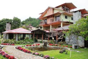 ein Haus mit einem Teich und Blumen davor in der Unterkunft El Oasis Hotel y Restaurante in Boquete