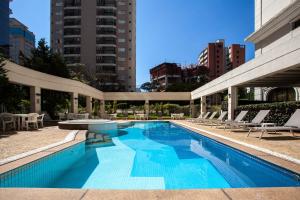 uma piscina com cadeiras e um edifício em The World Vila Olímpia em São Paulo