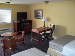 a hotel room with a desk and a bed and a table at Southern Inn and Suites Yorktown in Yorktown