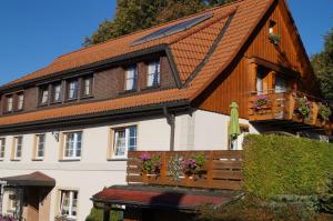 uma casa com um telhado de madeira e um banco em Pension Schüler em Bonndorf im Schwarzwald