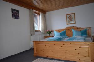 a bedroom with a large wooden bed with blue pillows at Pension Schüler in Bonndorf im Schwarzwald