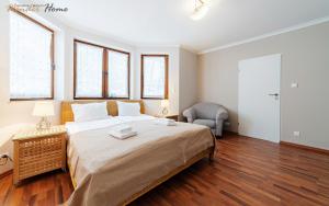 a bedroom with a large bed and a chair at Wonder Home - Apartamenty z balkonami przy szlakach turystycznych - blisko plac zabaw i boisko do gry in Karpacz