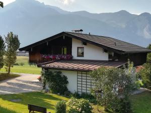 Biały dom z czarnym dachem i kwiatami w obiekcie Ferienwohnung Angererhof w Reith im Alpbachtal