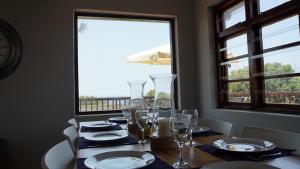 a dining room table with glasses and plates and a window at Villa 93 in Durban