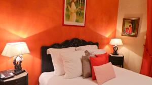 a bedroom with orange walls and a bed with white pillows at Hotel Relais Du Postillon in Antibes