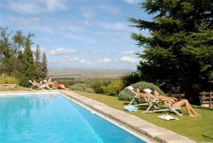 a group of people laying in lawn chairs next to a pool at El Castillo de Mandl in La Cumbre