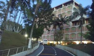 a large pink building with palm trees on the side of a road at Flat-Hotel Cavalinho Branco (G08) in Águas de Lindóia