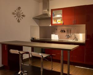 a kitchen with red cabinets and a counter with stools at Madeleine in Boncourt