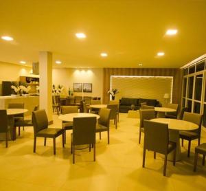 a restaurant with tables and chairs and a couch at Terra de Gabriela e Jorge Amado,Todo refrigerado! in Ilhéus
