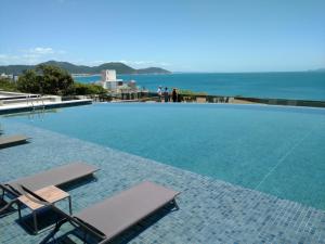 a swimming pool with two lounge chairs and the ocean at Apartamento Espelho das Águas in Florianópolis