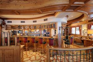 a bar in a restaurant with wooden ceilings and bar stools at Hotel Alpenrose in Zauchensee