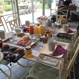 una mesa larga con alimentos para el desayuno. en B&B La Closerie 33, en Sadirac