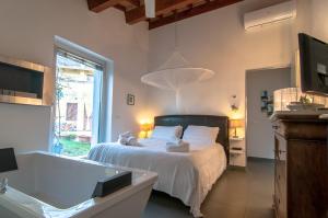 een slaapkamer met een bed, een bad en een televisie bij Casa Vog in Brufa
