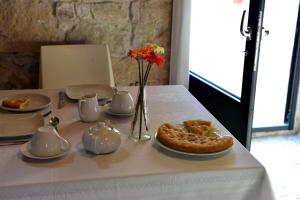 a white table with a pie and a vase of flowers at Relais Cimillà B&B in Ragusa