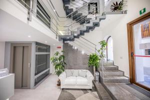 a living room with a white couch and stairs at Ossuna Bay Hotel Boutique in Cefalù