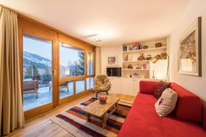 a living room with a red couch and a large window at Casa Alpetta in Flims