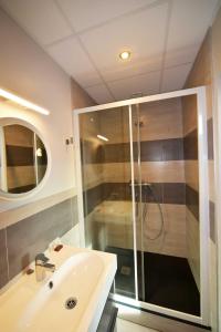 ein Bad mit einer Dusche und einem weißen Waschbecken in der Unterkunft Cafe de Paris in Capdenac-Gare