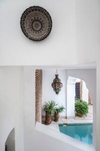 een kamer met een zwembad en een plaat en planten bij Riad El Maktoub in Marrakesh