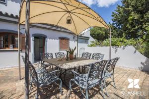 een tafel en stoelen onder een parasol op een patio bij Villa Arrochela in Vilamoura