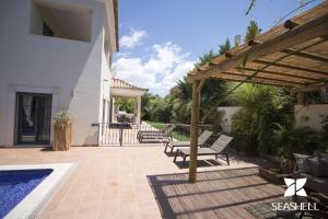 un patio con bancos y un pabellón con piscina en Villa Esmeralda, en Almancil