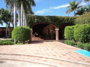 a building with an archway and trees and a courtyard at Hotel Hacienda Cazadores in Navojoa