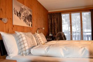 a bed with white pillows in a room with a window at Hotel Cabana in Grindelwald