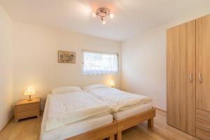 um quarto com uma cama branca e um armário de madeira em Quadris 6B em Flims