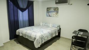 1 dormitorio con 1 cama con manta azul y blanca en Inn Bless Aparthotel en San Andrés