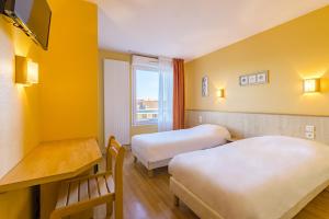 a hotel room with two beds and a desk at Azureva Métabief in Métabief
