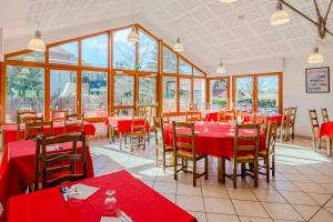 a restaurant with red tables and chairs and windows at Azureva Métabief in Métabief