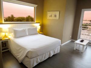 a bedroom with a large white bed with a window at Atlántico Boutique Hotel in Punta del Este