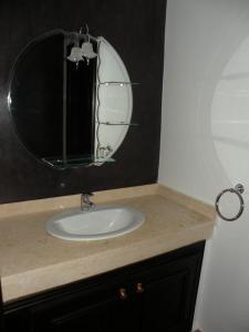 a bathroom sink with a large round mirror at Villa El Andalousse in Larache