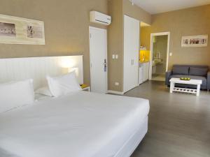 a bedroom with a large white bed and a living room at Atlántico Boutique Hotel in Punta del Este