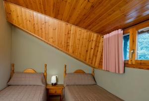 two beds in a room with a wooden ceiling at Casa Sastre in Espúy