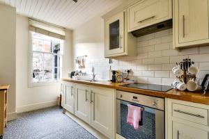 a kitchen with white cabinets and a sink at JOIVY Great Location - Lovely Rose St Apt in City Centre in Edinburgh