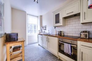 a kitchen with white cabinets and a sink at ALTIDO Perfect Location! - Stylish & Cosy Rose St Apt in Edinburgh