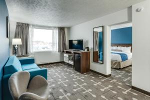 a hotel room with a blue couch and a bed at Baymont by Wyndham Spokane in Spokane +30 photos