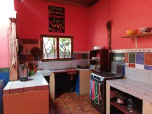 a kitchen with red walls and a stove top oven at Lazy Crab Hostel in Balgue