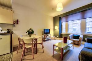uma sala de estar com uma mesa e um sofá e uma cozinha em ALTIDO Perfect Location! Charming Rose St Apt for Couples em Edimburgo