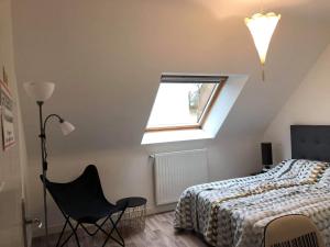 1 dormitorio con 1 cama, 1 silla y 1 ventana en Home Auray, en Auray