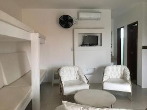 ein Zimmer mit zwei Stühlen und einem Tisch und einem Fernseher in der Unterkunft Lofts Dois Corações in Cabo Frio