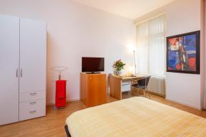 um quarto com uma cama e uma secretária com uma televisão em Residence zur Musegg em Lucerna