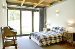 a bedroom with a bed and a chair and a window at Quinta da Longra in Alvarenga