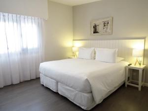 a bedroom with a large white bed and a window at Atlántico Boutique Hotel in Punta del Este